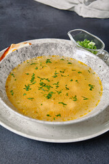 Traditional Bowl Food - Chicken Noodle Soup on Dark Table. Soup in ceramic bowl on dark textured background with food ingredients.