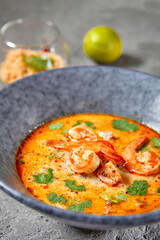 Tom Yum or Tom Yam Soup - Hot and Sour Thai Soup cooked with Shrimp. Thai Authentic Traditional Dinner. Soup in Blue Bowl on Dark Grey Table. Street Asian Food.