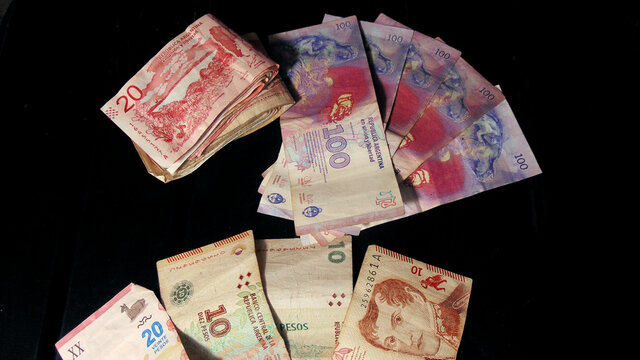 money of one hundred, twenty and ten Argentine pesos on a black background 
