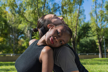 interracial couple, black african woman, leaning on the shoulder of her partner a long haired latin american man. the woman looks straight into the camera.