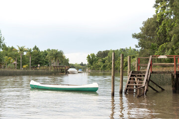 Obraz premium A canoe and a wooden dock in a creek in the Tigre Delta, in Buenos Aires,