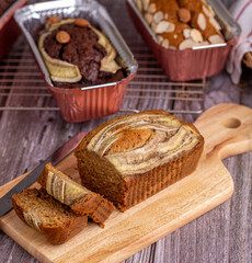 Homemade banana bread sliced with knife on a wooden board close-up.