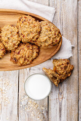 Top view homemade oatmeal cookies and glass milk. Gluten and sugar free recipe. Rustic wooden background and linen napkin. Delicious and healthy sweets. Breakfast. Vertical shot
