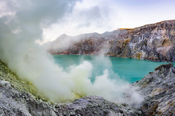 Ijen volcano crater and sulphur mining. Beautiful Landscape mountain and green lake with smoke sulfur in the morning in a Kawah Ijen volcano. Beautiful landmark from East Java, Indonesia