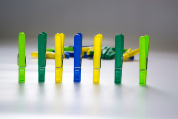 Colorful plastic clothespins on a light background. Space for your inscription. Minimalism, original and creative photography. Be different. The concept of individuality. Vertical wallpaper for a