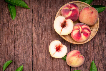 Fresh Peach fruits with leaves on wooden plate, Peach in wooden plate on wooden bamboo background.