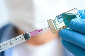 Doctors hand holding a blue syringe and  vaccine covid 19  at the hospital Concept of health and...