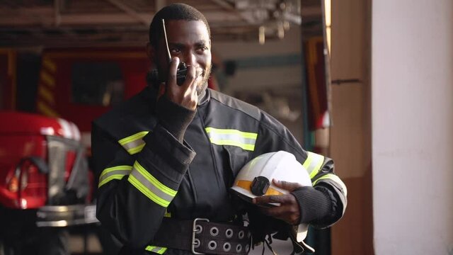 African American fireman in equipment with helmet use walkie talkie at the station