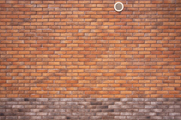Brick wall with air vent. The wall is made of red brick with brown edging.