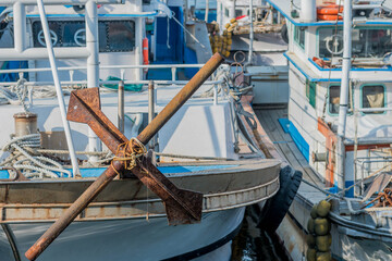 Fototapeta na wymiar Large rusty iron anchor on bow of docked boat.