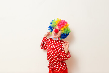 Hilarious five-year-old boy dances in clown costume and wig on white background