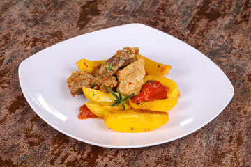 Baked pork meat with potao and tomato