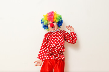 Hilarious five-year-old boy dances in clown costume and wig on white background