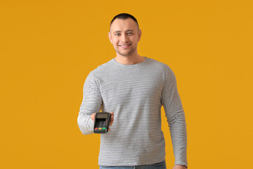 Man with payment terminal on color background