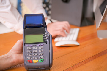 Seller with payment terminal in shop, closeup