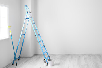Ladder, roller, brushes and bucket in light room