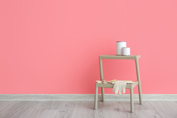 Step ladder with cans of paints and tools near color wall