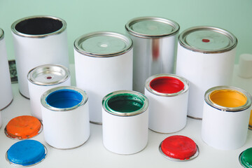 Cans of paints on table near color wall