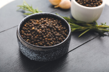 Bowl with peppercorns on dark wooden background