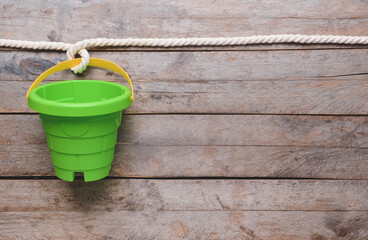 Toy bucket for children with rope on wooden background