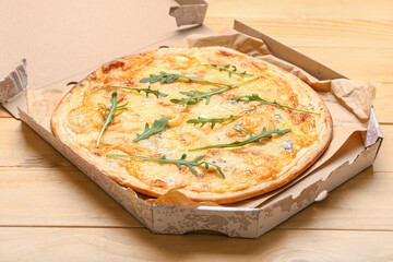 Box with tasty cheese pizza on wooden background