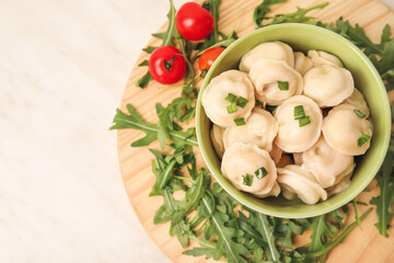 Bowl with tasty dumplings on light background