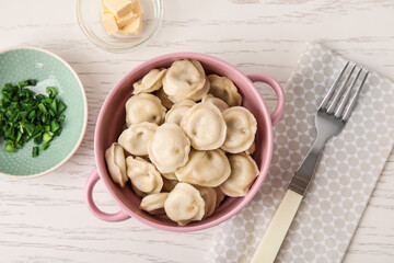 Bowl with tasty dumplings on light wooden background