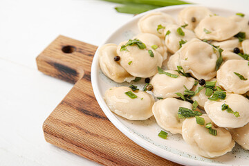 Plate with tasty dumplings on light background