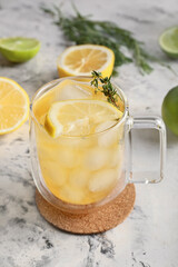 Cup of cold green tea, herbs and citrus fruits on light background