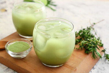Obraz na płótnie Canvas Glasses of cold matcha tea, powder and herbs on light background, closeup