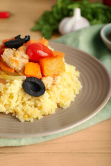 Plate with couscous and vegetables on wooden background