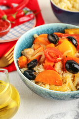 Bowl with couscous and vegetables on light background