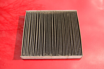 a dirty cabin filter is on the hood of a red car. old used cleaner