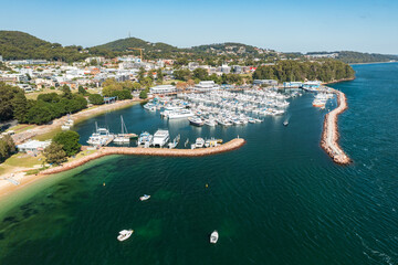 Aerial view of Nelson Bay marina, breakwater, town, and aqua waters of Port Stephens, Australia.
