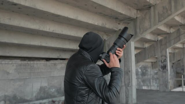A private detective or spy with a camera stealthily walks through the territory of an abandoned stadium.