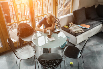 Pensive young man sitting at table drink coffee work at notebook