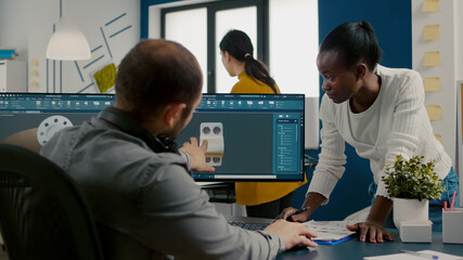 Diverse engineers working on computer at mechanical pieces design sharing ideas about industrial...