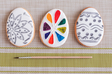 Easter egg biscuit with gray pattern on white glaze and honey cake with a palette of food coloring to paint with a brush