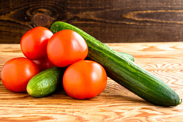two cucumbers and four tomatoes on a wooden background
