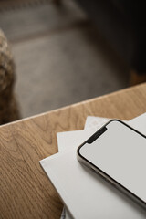 Blank screen mobile phone on wooden table. Minimalist blog, website template. Copy space mockup.