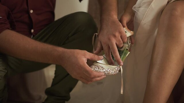 Greek Wedding Shoe tradition. Groom adding money into the bridal shoes. Symbol of wealth - bride walks in wealth
