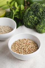 Buckwheat grain in bowl and vegetarian food ingredients for cooking on kitchen table. Clean eating food, healthy diet concept. Close up, vertical