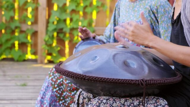 Musician plays the glucophone. Closeup of hands of girl playing on tank drum