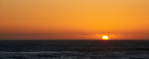Sunset view and the sun touching the ocean surface near Lincoln city in Oregon.