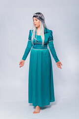 Fototapeta premium Full length portrait of a princess in a medieval, fantasy, turquoise dress with ash hair and a silver crown, posing isolated on a white background. 