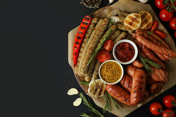 Concept of tasty food with tray of grilled sausage on black background