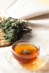 Herbal Thyme tea glass with thymus plant on linen table cloth.