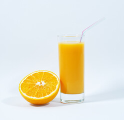 A glass of fresh orange juice, a straw, half of an orange, white background