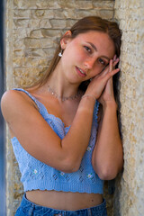 Young dark blonde haired woman standing against a wall in an downtown area