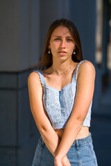Fototapeta premium Young dark blonde haired woman standing against a wall in an downtown area